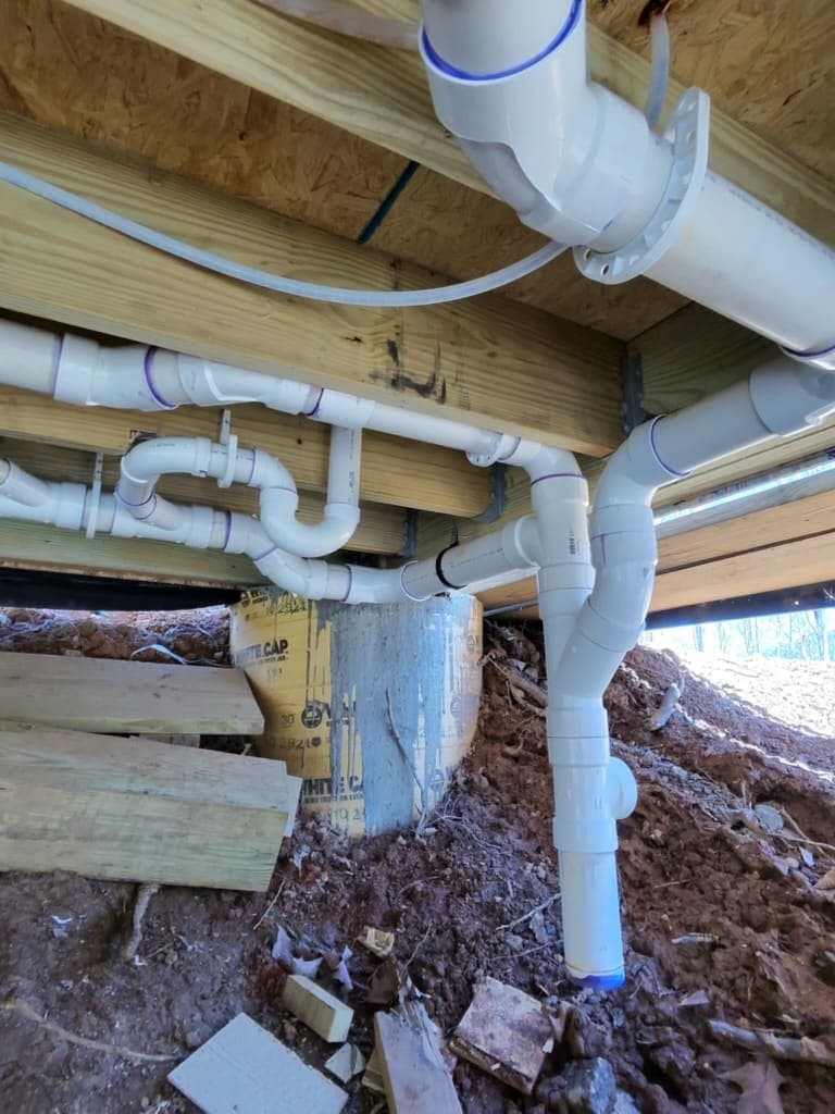 New PVC drain piping under a house, installed by MRJ Plumbing near Asheville, NC