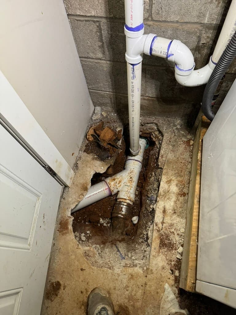 New PVC drain tied into an older cast-iron line below a floor, by MRJ Plumbing near Asheville, NC
