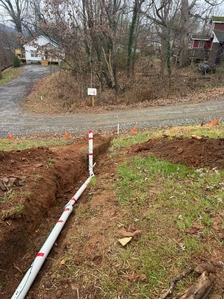 Trench for a new sewer line across a yard, dug by MRJ Plumbing near Asheville, NC